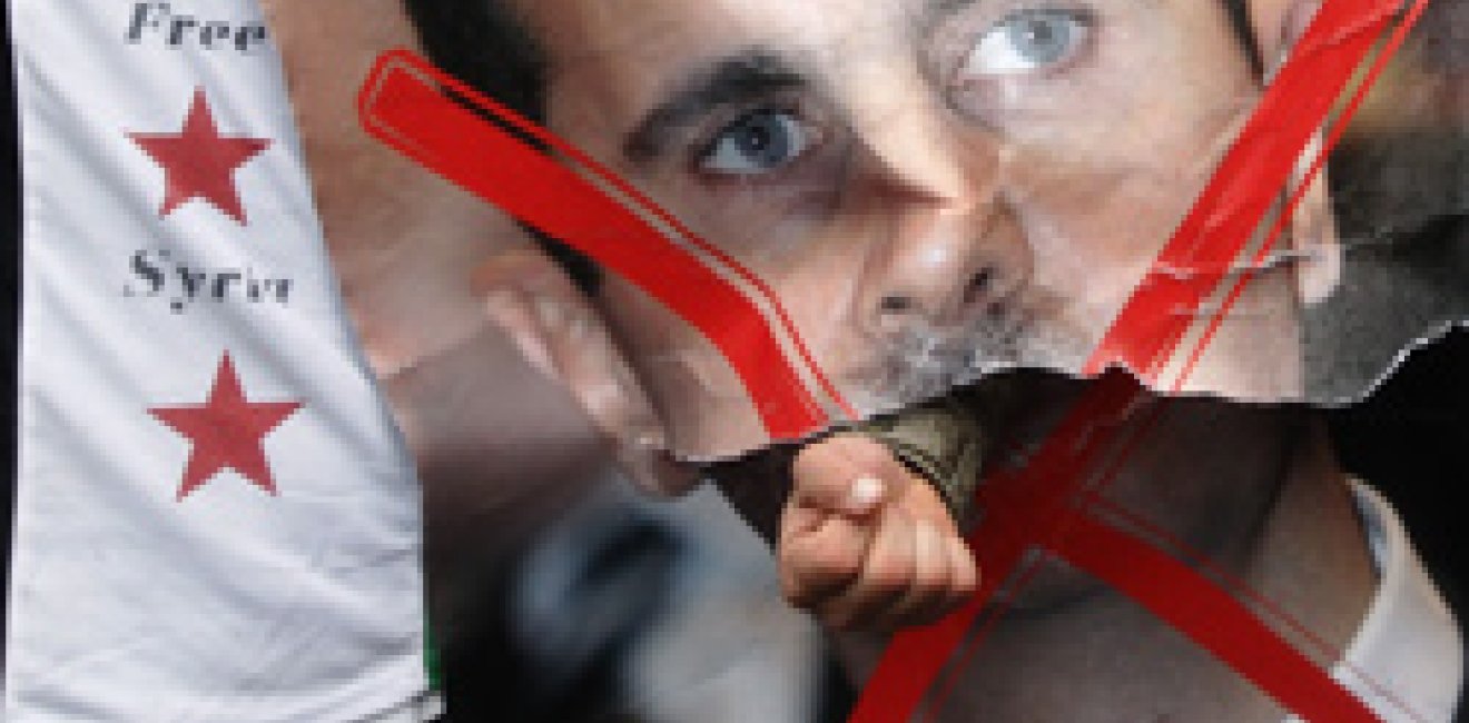 A demonstrator punches through a portrait of Syria's President Bashar al-Assad during a protest outside the Syrian Embassy in London