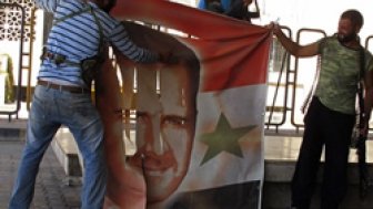 Free Syrian Army members tear a banner with picture of Syria's President Al Assad at Syrian border crossing building between Syria and Turkey at Jarablus