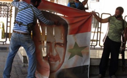 Free Syrian Army members tear a banner with picture of Syria's President Al Assad at Syrian border crossing building between Syria and Turkey at Jarablus