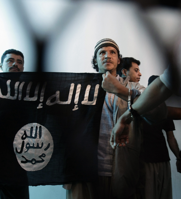 n this April 23, 2013 file photo, a suspected Yemeni al-Qaida militant, center, holds a banner as he stands behind bars during a court hearing in state security court in Sanaa, Yemen