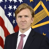 A photo of Elbridge Colby in front of an American flag.