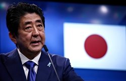 Prime Minister Shinzo Abe speaks at an event with the Japansese flag in the background.