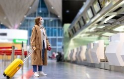Woman with luggage stands at almost empty check-in counters at the airport terminal due to coronavirus pandemic/Covid-19 outbreak travel restrictions. Flight cancellation. Quarantine all over the world