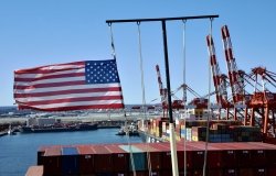Newark, NJ / USA - March 28 2020: US flag on the mast of cargo ship berthed in the container terminal in Newark.